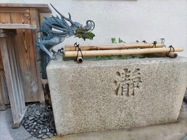 「瀞」の文字が彫られた石のお手水に龍の口か水が流れ出ている様子。
