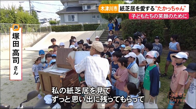 大勢の子どもたちに囲まれて、紙芝居を披露する塚田さん。