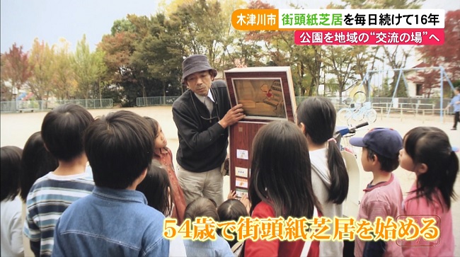 公園で子どもたちに囲まれる紙芝居を読む昔の塚田さんを撮った写真。