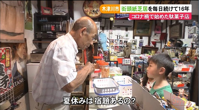 駄菓子屋のレジにて会計をしながら子どもと話す塚田さん。