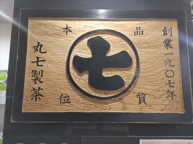 『ななや京都三条店』の店内に飾られた木彫りの『丸七製茶』の屋号。