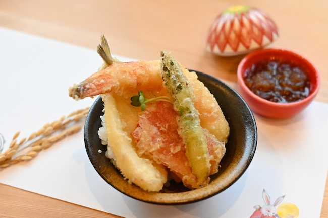 黒いお皿に盛られた天ぷら丼と赤い器に入ったおろしぽん酢