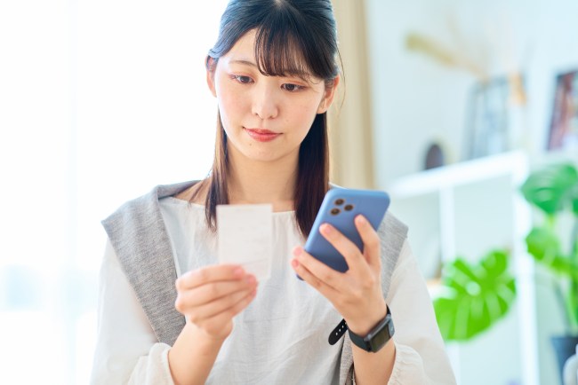 スマホで家計簿をつける女性