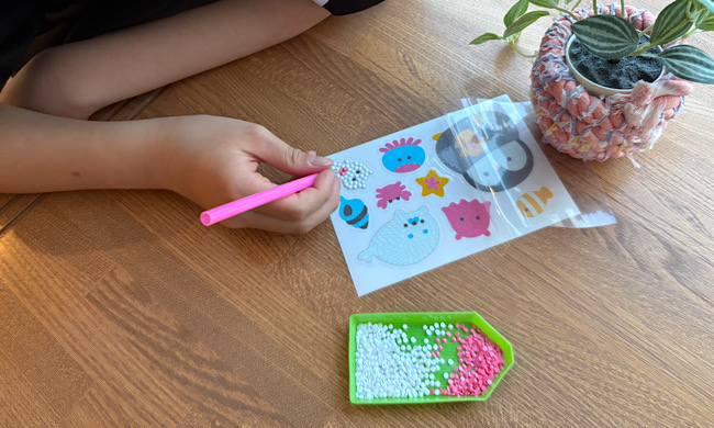 「つくろう!ビーズアートシール」で遊んでいる子ども