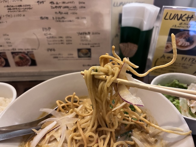 タイカレーラーメンを箸で持ち上げる