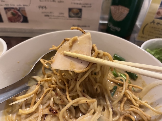 味変したタイカレーラーメンの麺を箸で持ち上げる