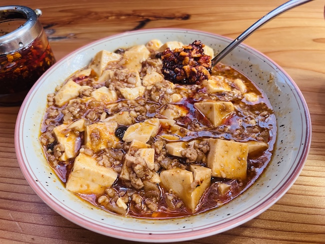 麻婆豆腐に食べるラー油を入れる