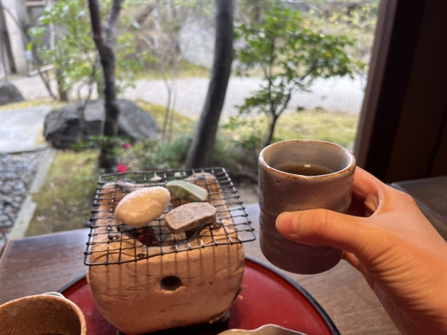 餅や生麩がのった七輪と手に持ったほうじ茶
