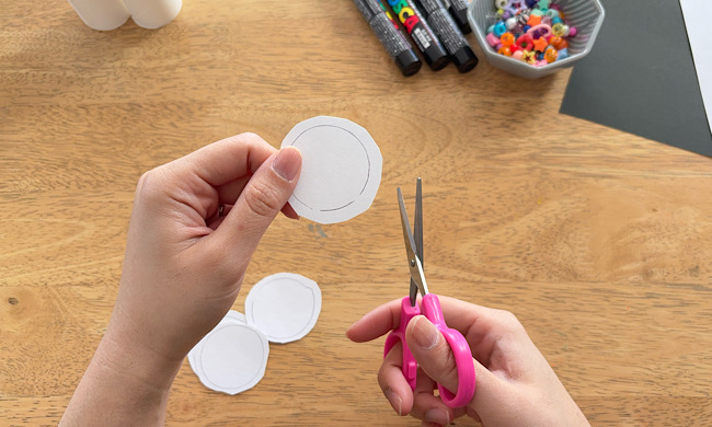 工作用の白い画用紙を丸く切っている手元の様子