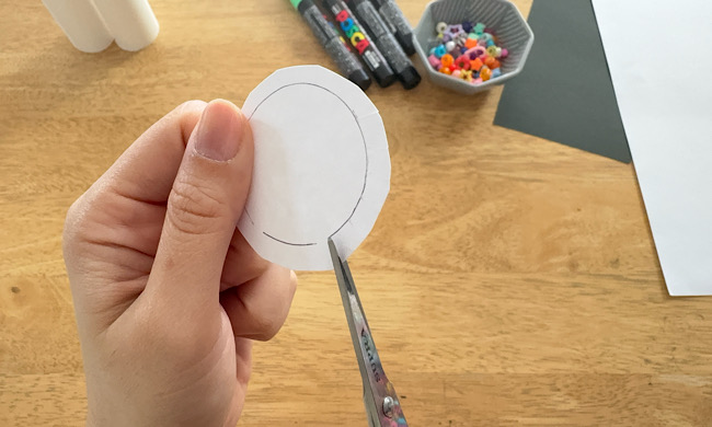 白い画用紙に描いた円の線に沿って、はさみで切りこみをいれる工程