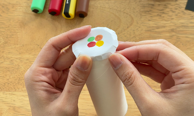 画用紙をトイレットペーパーの芯にかぶせている手元の様子