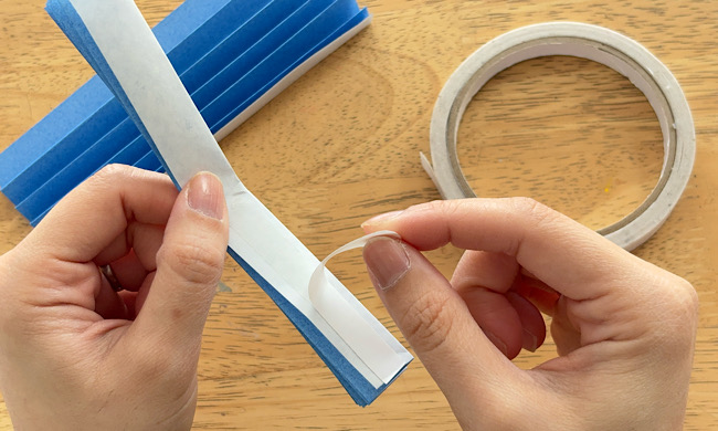 蛇腹折りにした折り紙の内側に両面テープを貼る工程