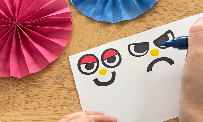 画用紙に鬼の目や鼻のパーツを描く様子