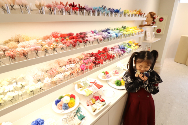 髪飾りをもって棚の前に立つ子ども